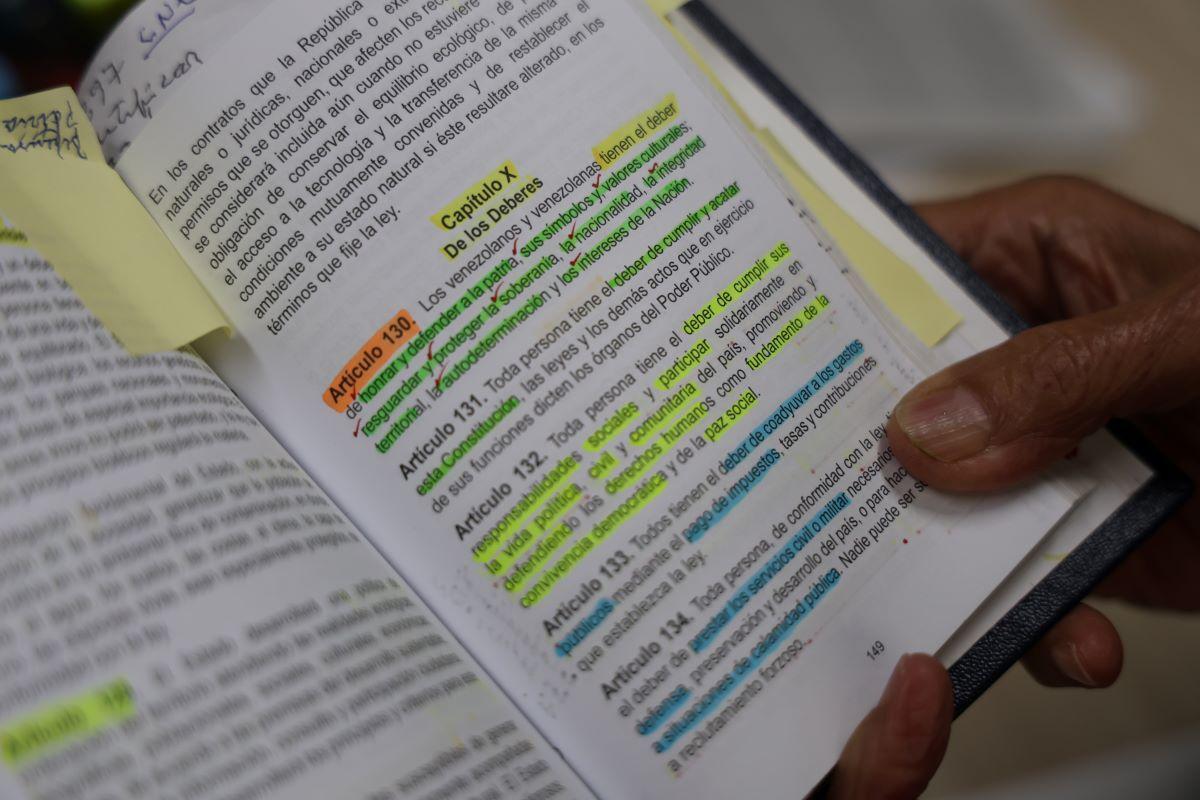 El cónsul venezolano enseña un artículo de su Constitución.
