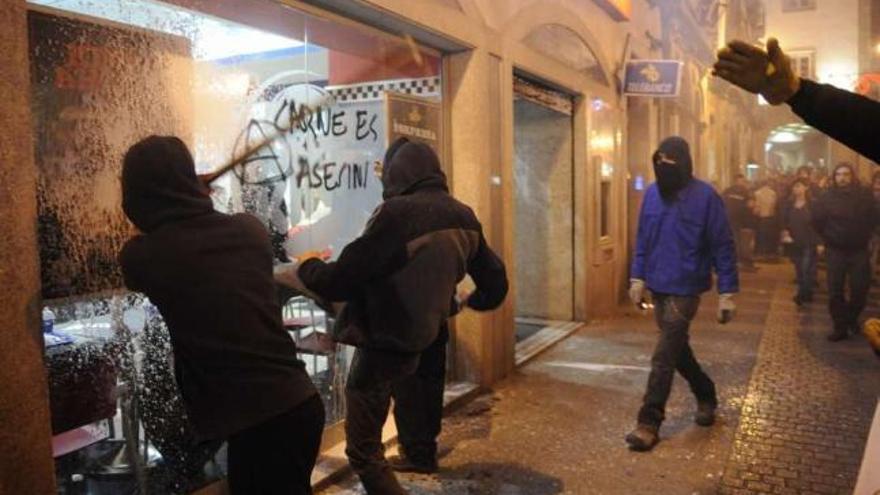 Manifestantes golpean el escaparate del Burger King de la calle Riego de Agua. / carlos pardellas