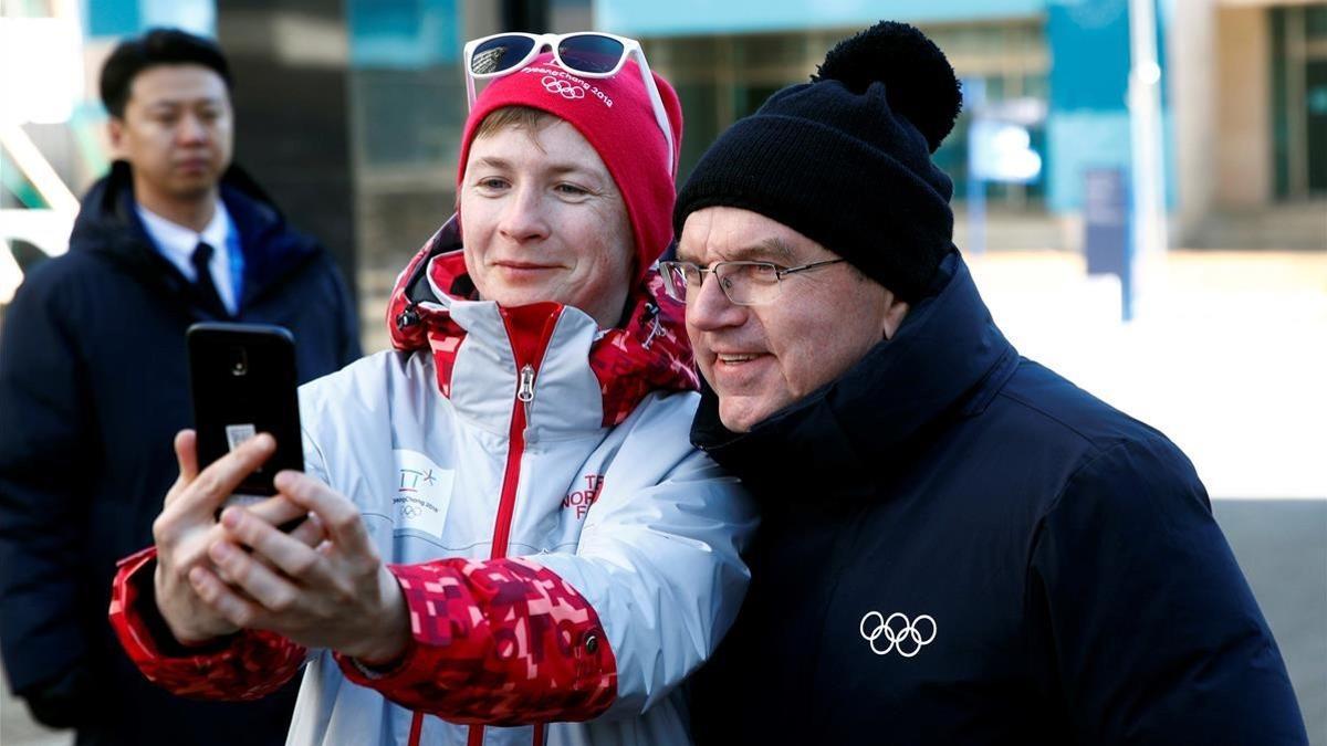 El presidente del COI, Thomas Bach, se hace un selfi con una voluntaria en Pieonchang.