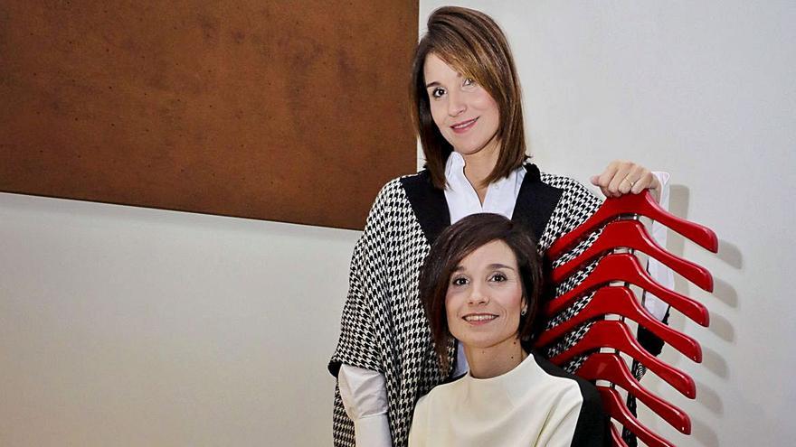 Las dos hermanas en una singular silla fabricada a base de perchas. | JUANI RUZ