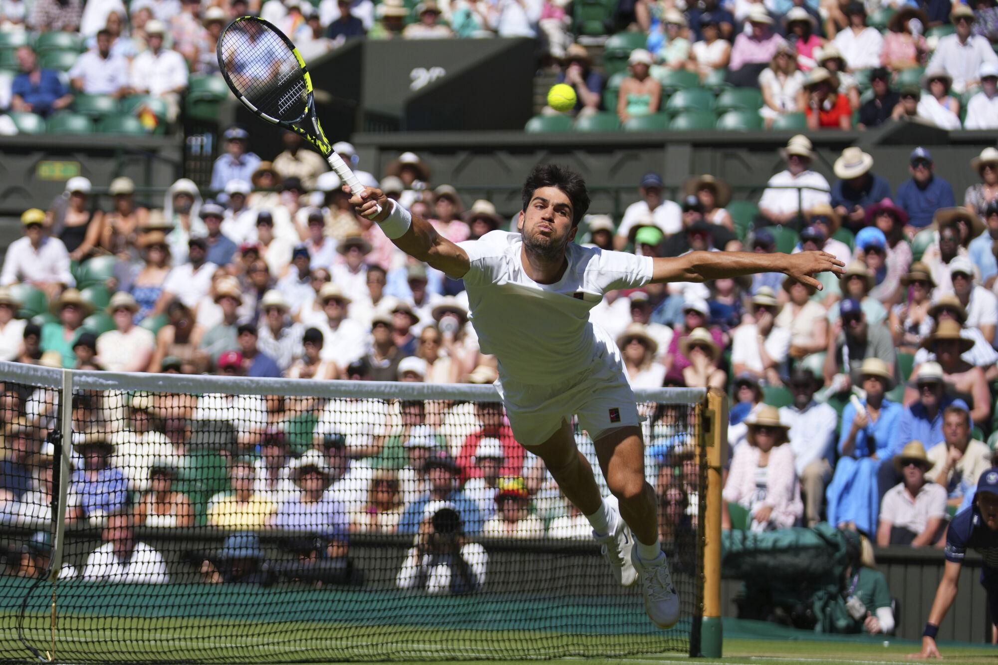 Carlos Alcaraz of Spain returns the ball to Taylor Fritz of the U.S. during the men's semifinal singles match at the Wimbledon Tennis Championships in London, Friday, July 11, 2025.(AP Photo/Joanna Chan). EDITORIAL USE ONLY/ONLY ITALY AND SPAIN