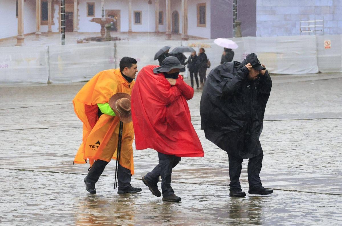 Los peregrinos se protegen con chuvasqueros de la lluvia de Santiago