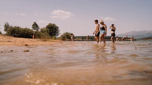 Varias personas se dan un remojón en la playa de Aguilar de Campoo, en Palencia.