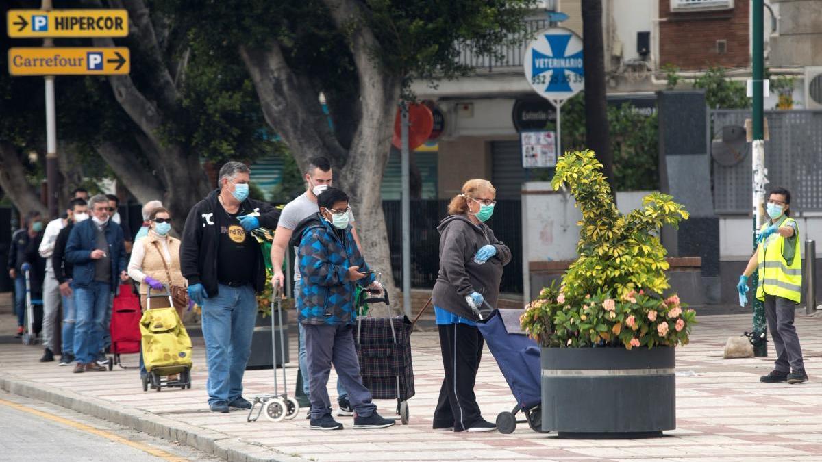 Varias personas esperan en una cola para entrar a un supermercado en Málaga.