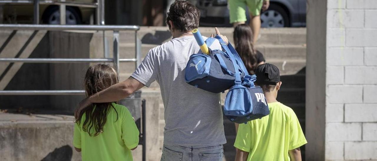 Un padre carga con las bolsas de deporte de sus hijos, en un club deportivo de Barcelona.
