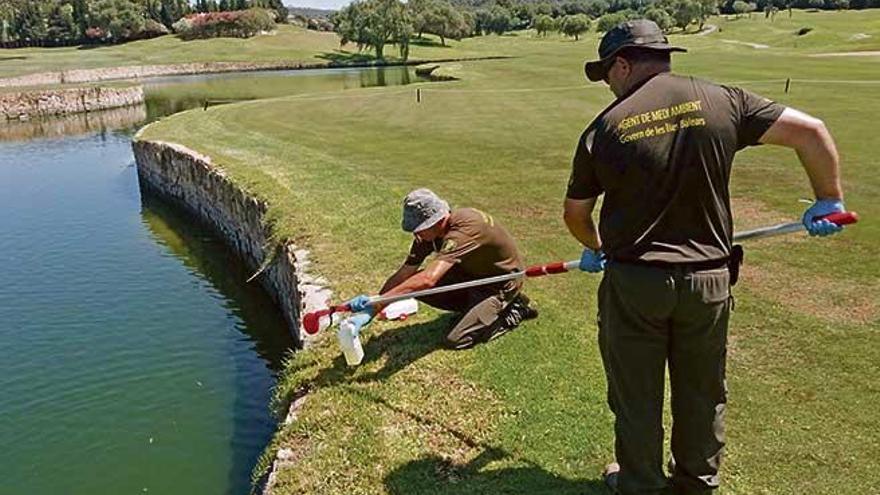 Dos agentes de Medio Ambiente toman muestras de agua en un campo de golf.