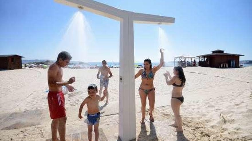 Grupo de niños duchándose en la playa de Areas. // G.Santos