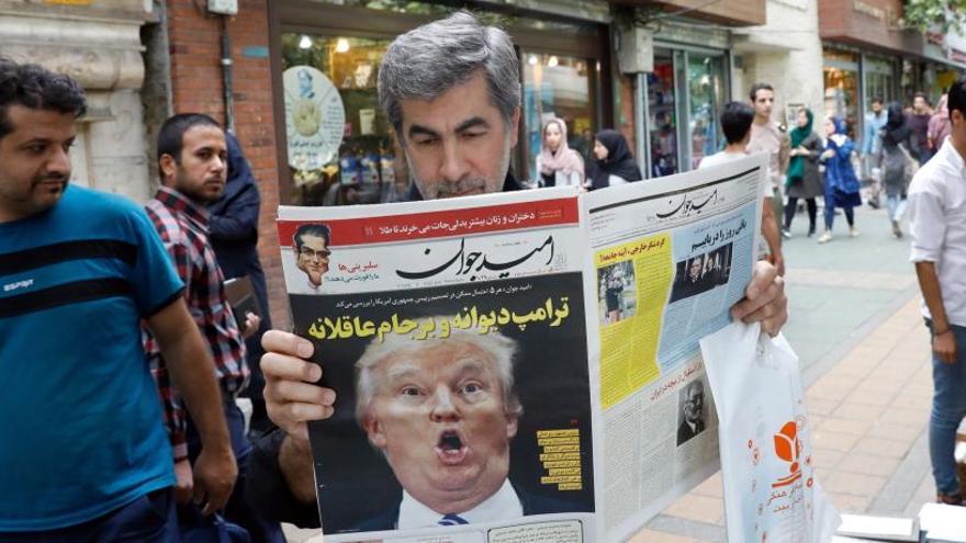 Un iraní lee un periódico en el que se tacha de &quot;loco&quot; a Trump.