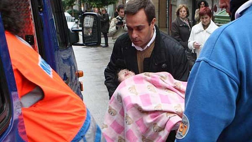 El bebé es trasladado al interior de la ambulancia por uno de los trabajadores de la sucursal bancaria