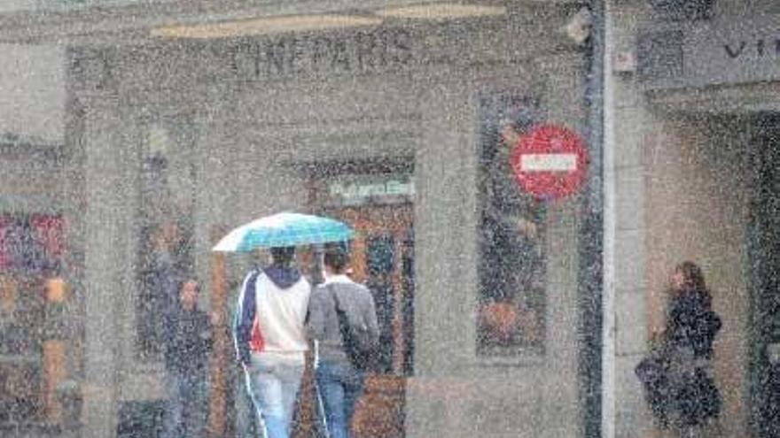 Una pareja pasea bajo la lluvia en al calle Real de A Coruña.