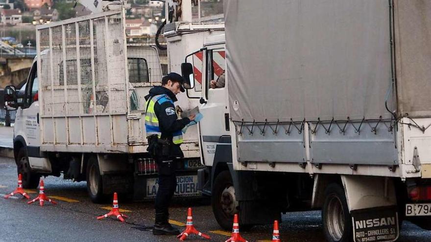 Un policía local controla dos camiones durante estas campañas de vigilancia a los transportistas. // R. V.