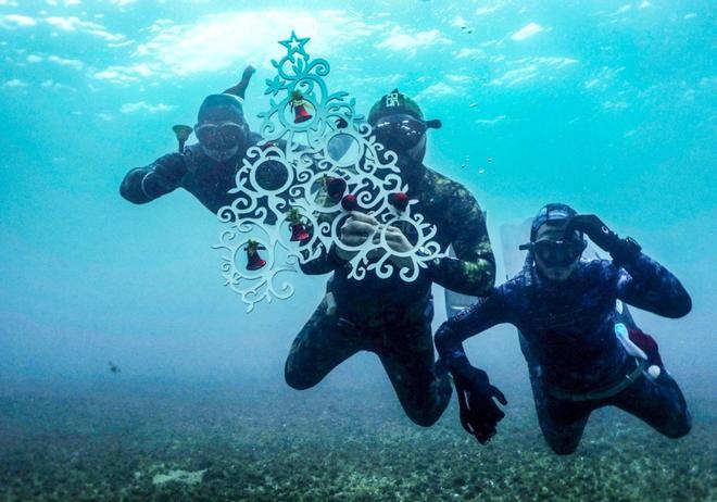 Los freedivers posan para una foto bajo el agua mientras sostienen a un Christa ornamental antes de colocarlo en el lecho marino de la costa de la ciudad portuaria del norte de Líbano, Trípoli.