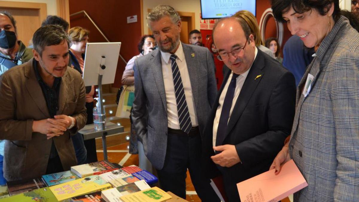 El subdirector general de Cooperación Cultural con las Comunidades Autónomas, Benito Burgos; el alcalde de Navia, Ignacio García; el ministro Miquel Iceta, y la directora general de Industrias Culturales, Propiedad Intelectual y Cooperación, Adriana Moscoso, mirando unos libros. | A. S.