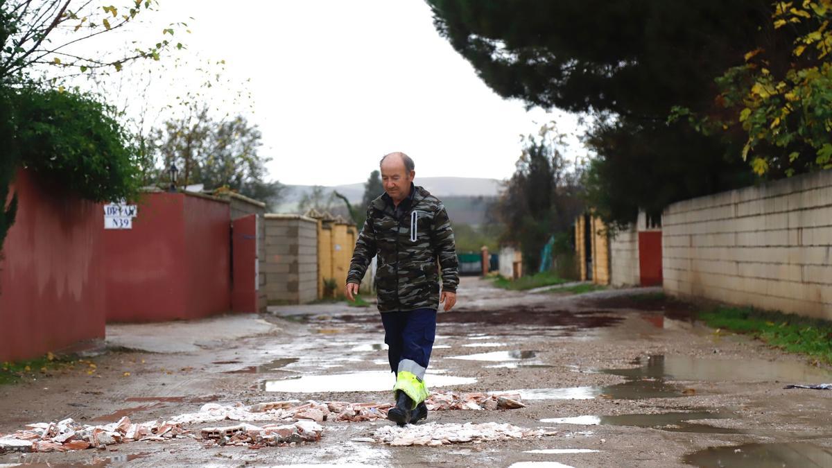 Gabriel, vecino de una parcela en la calle La Tórtola, cubre los socavones convertidos en grandes charcos.