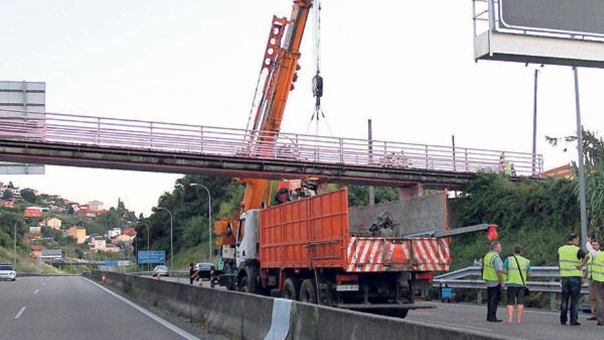 La grúa desplazada hasta el lugar, sostiene la estructura del puente, con los carriles de la autopista sin tráfico.  // Joel Martínez