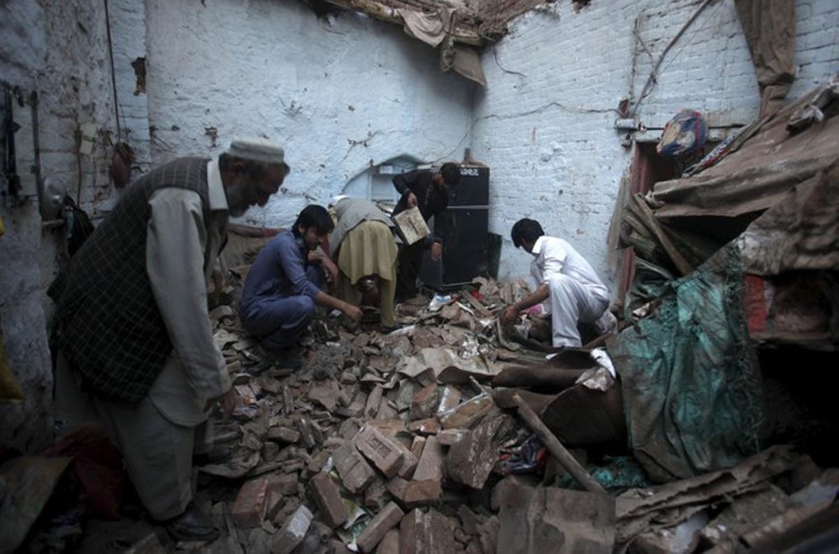 Habitantes de la localidad paquistaní de Peshawar buscan entre las ruinas de su vivienda.