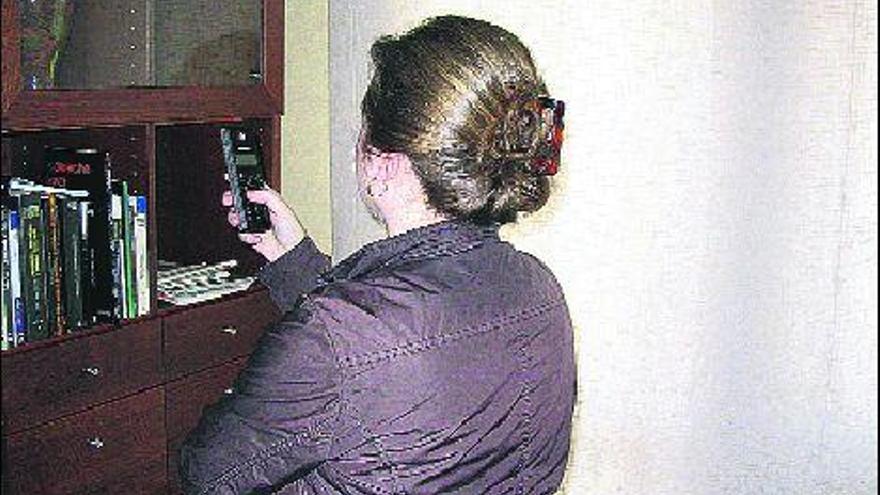 Una usuaria sostiene un teléfono que carece de línea.