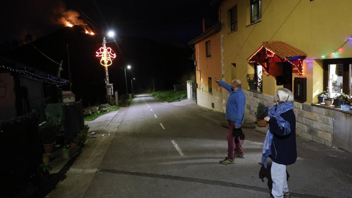 Dos vecinos de Picullanza señalando a las llamas en la cima del pico La Corona.
