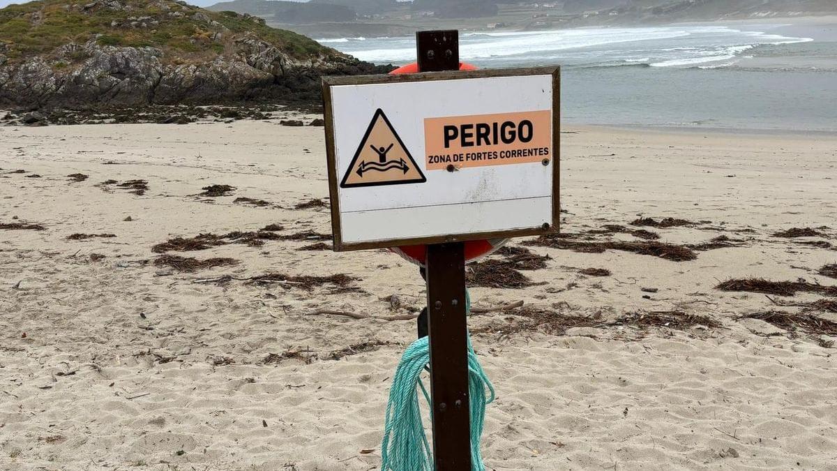 Cartel oficial advirtiendo del peligro de las corrientes en la playa de Lires.