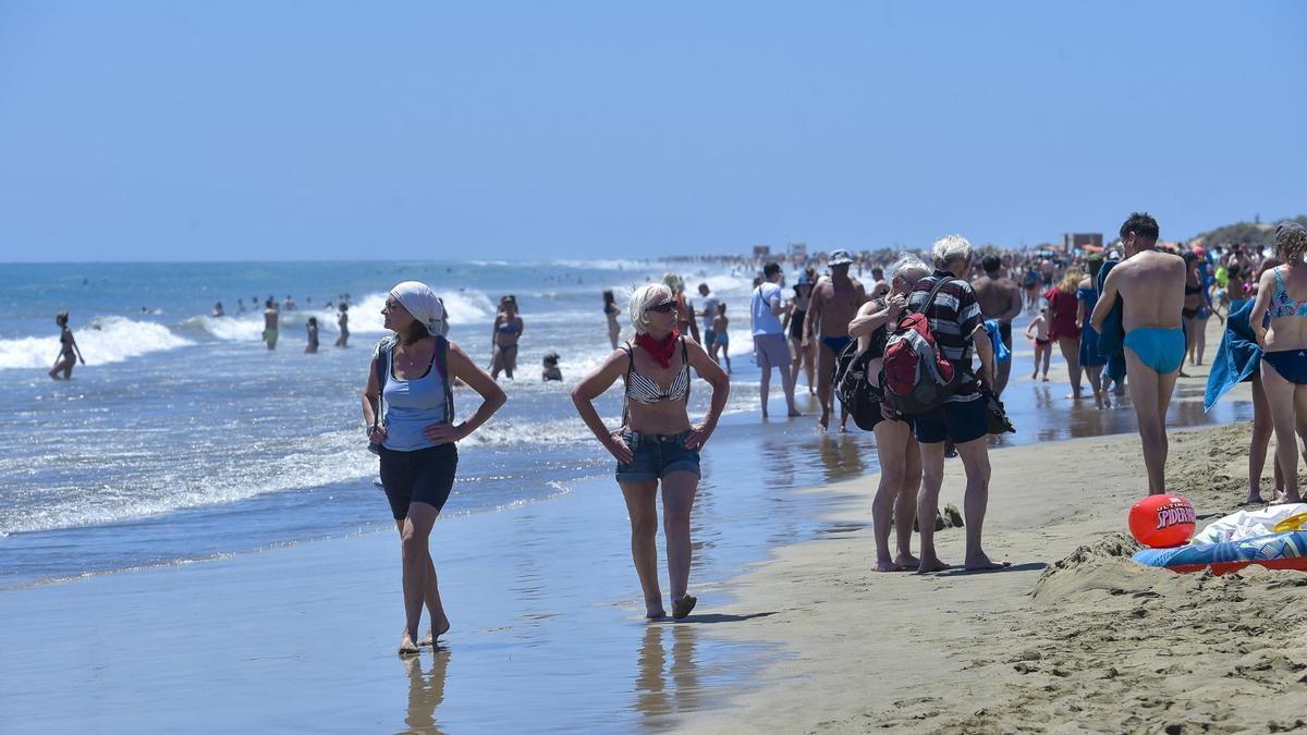 Numerosos turistas disfrutan de la arena, el sol y el mar en la playa de Maspalomas, en Gran Canaria.