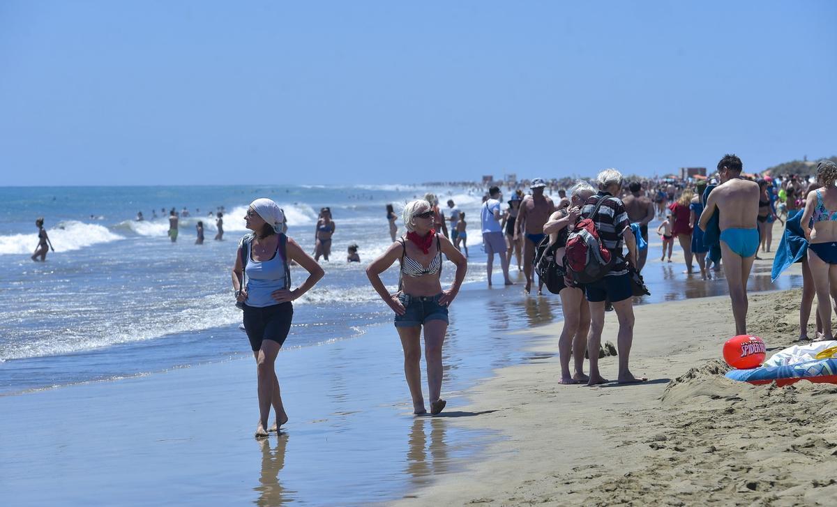 Numerosos turistas disfrutan de la arena, el sol y el mar en la playa de Maspalomas, en Gran Canaria.