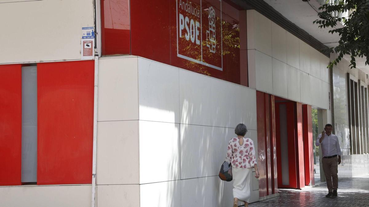 Varias personas caminan junto a la sede del PSOE de Córdoba tras la limpieza de la pintada.