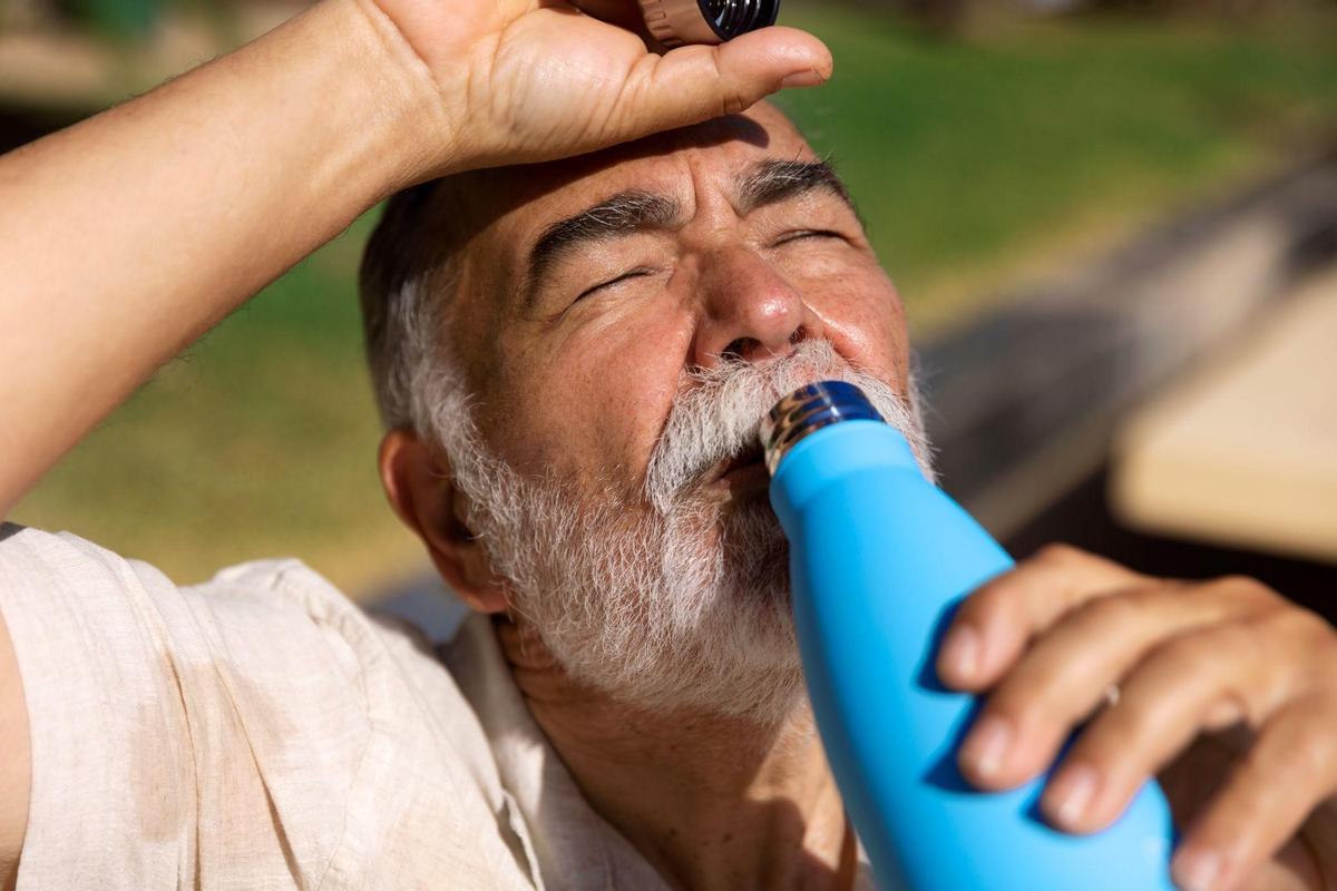 Una persona mayor bebe agua para combatir el calor.