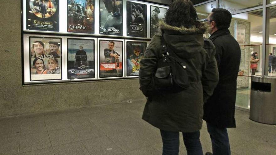 Una pareja consulta la cartelera en un cine gallego.