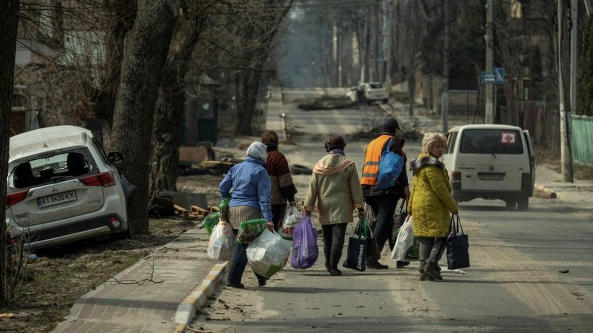 Un grupo de ucranianos huye de Bucha tras la destrucción causada por las fuerzas rusas.