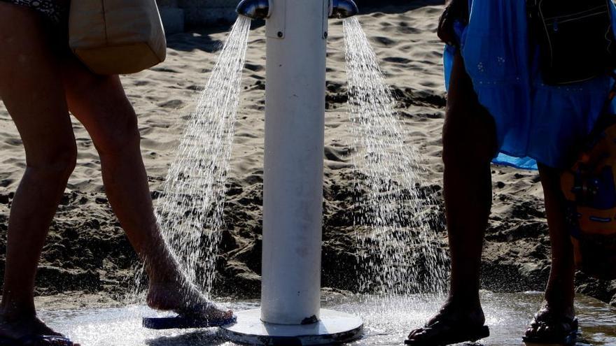 Dos personas se limpian los pies de arena en la playa.