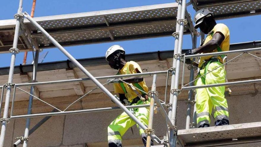 Dos empleados extranjeros trabajan en la construcción de un edificio en Galicia.