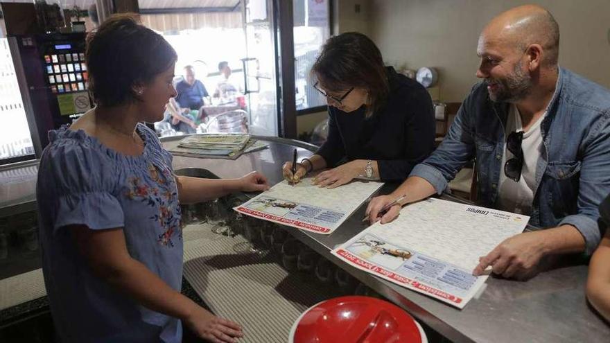 Vecinos cubren las rifas en un bar para el sorteo de premios valordos en 30.000 euros. // Bernabé