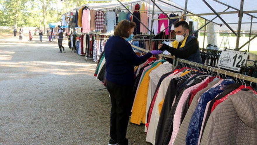 Un marxant ven una peça de roba a una clienta al mercat de la Devesa de Girona