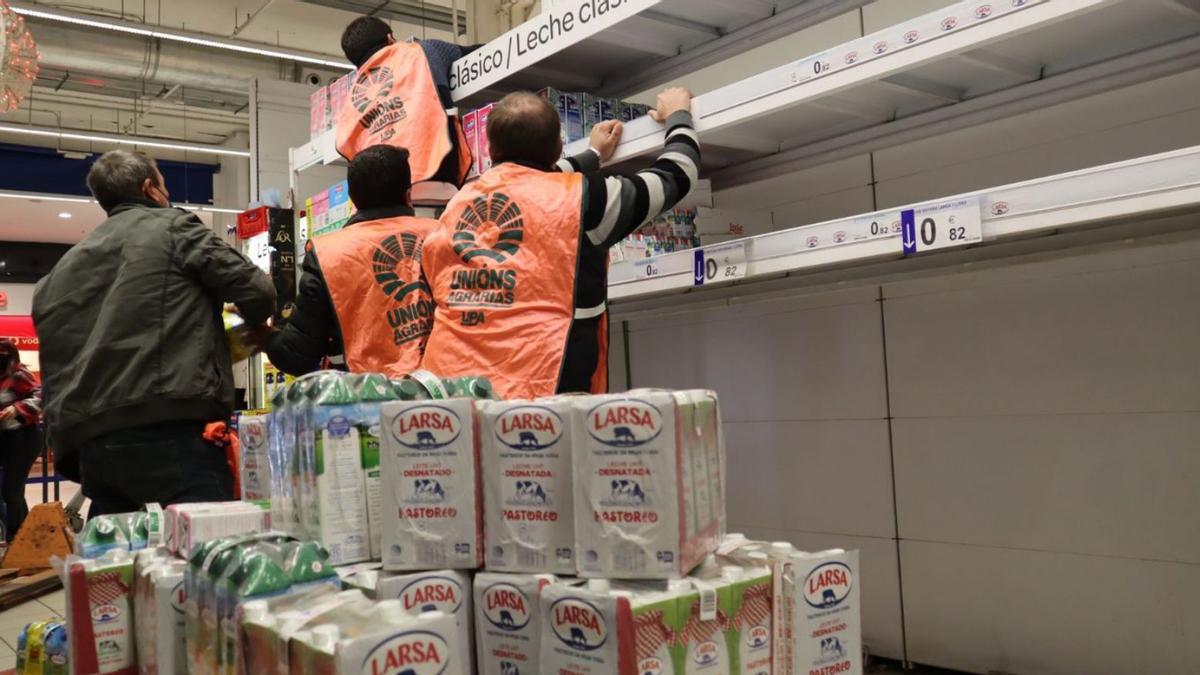 Miembros de Unións Agrarias retiran leche de lineales en un supermercado de Santiago. |   // UUAA