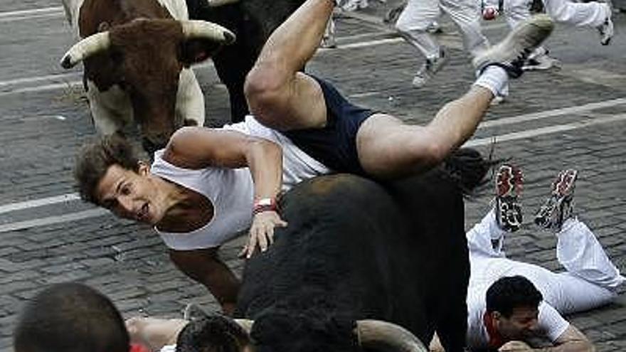 Uno de los corredores volteados por un toro durante el tercer encierro.