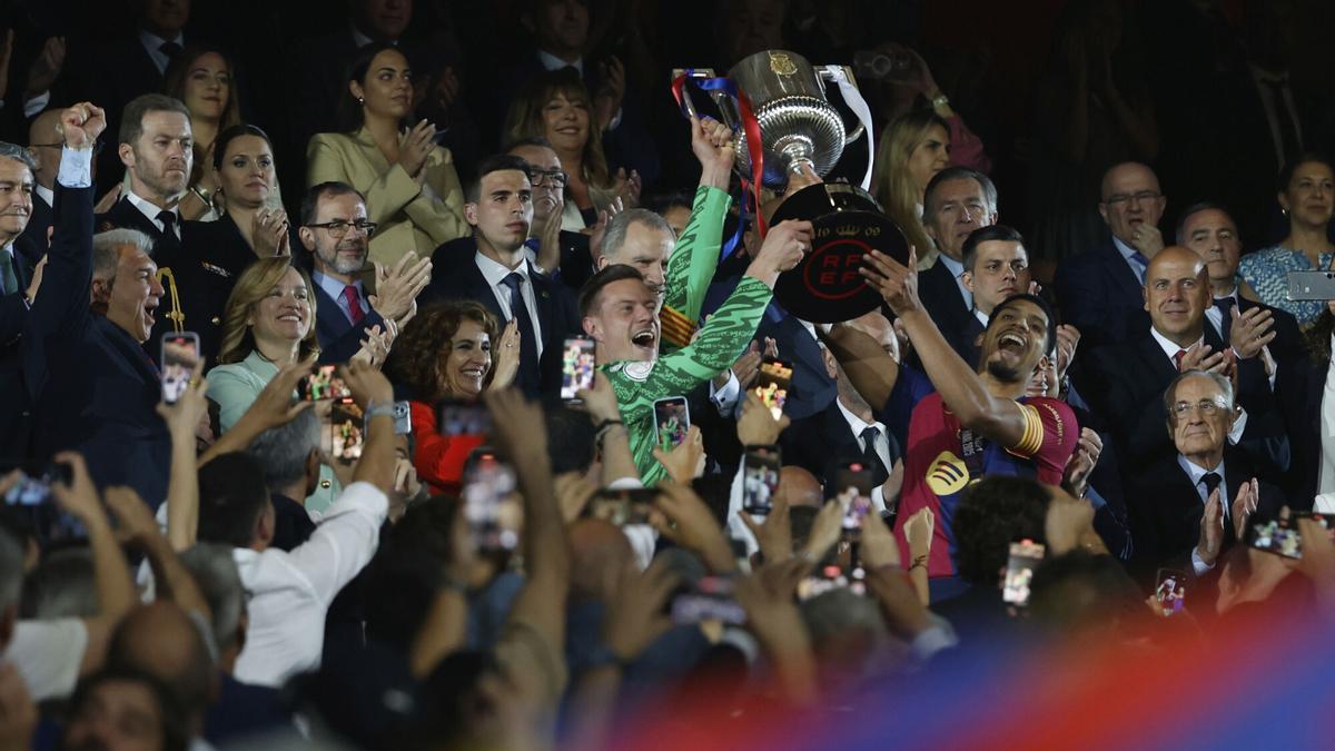 Barcelona's Ronald Araujo, right, and Barcelona's goalkeeper Marc-Andre ter Stegen lift the trophy after winning the Spanish Copa del Rey final soccer match between Barcelona and Real Madrid at Estadio de La Cartuja stadium in Seville, Spain, Sunday, April 27, 2025. (AP Photo/Joan Monfort)
