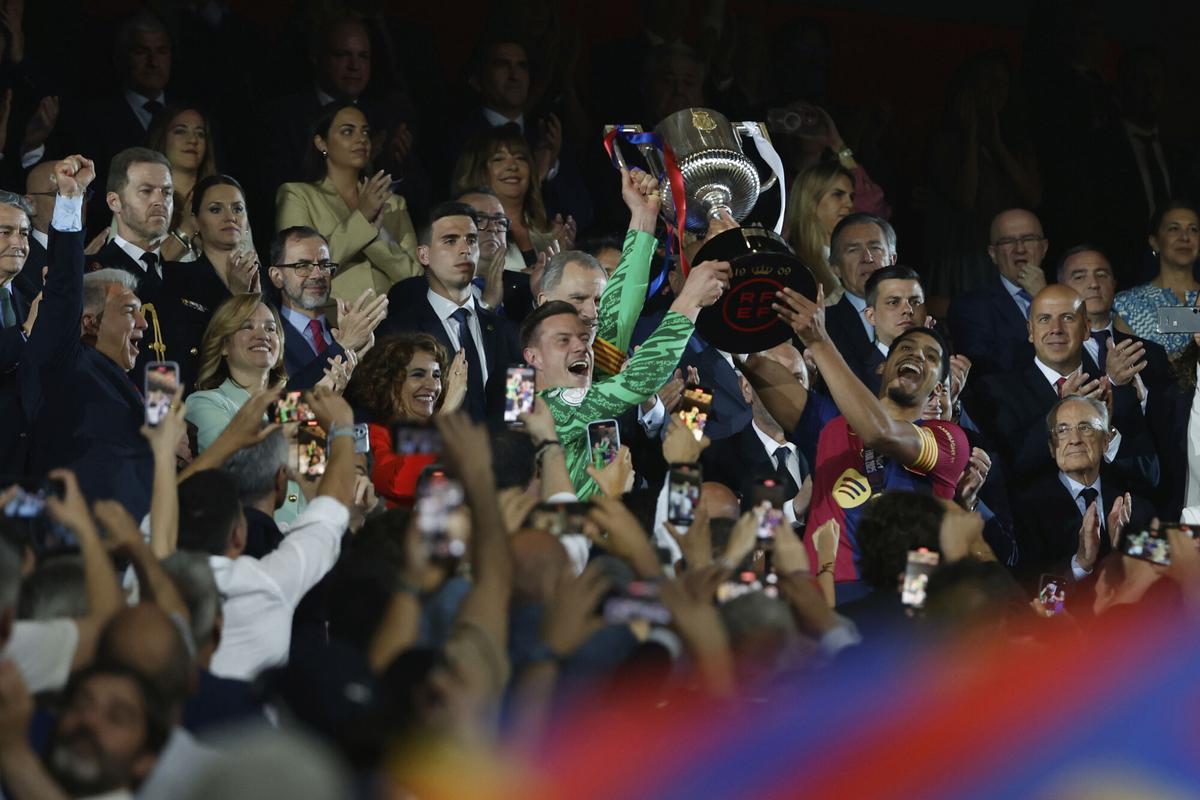 Barcelona's Ronald Araujo, right, and Barcelona's goalkeeper Marc-Andre ter Stegen lift the trophy after winning the Spanish Copa del Rey final soccer match between Barcelona and Real Madrid at Estadio de La Cartuja stadium in Seville, Spain, Sunday, April 27, 2025. (AP Photo/Joan Monfort)