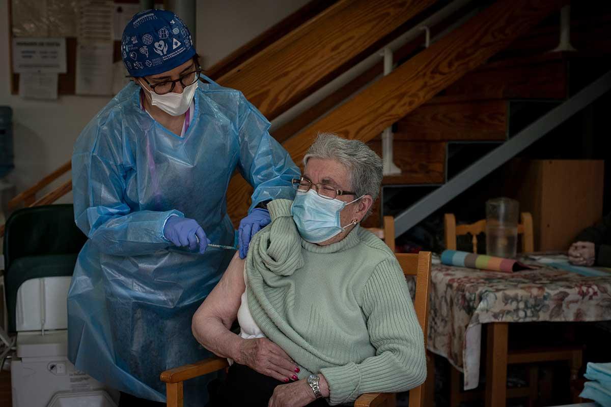 Un sanitario dispensa la vacuna contra el COVID a un anciano en Allariz.