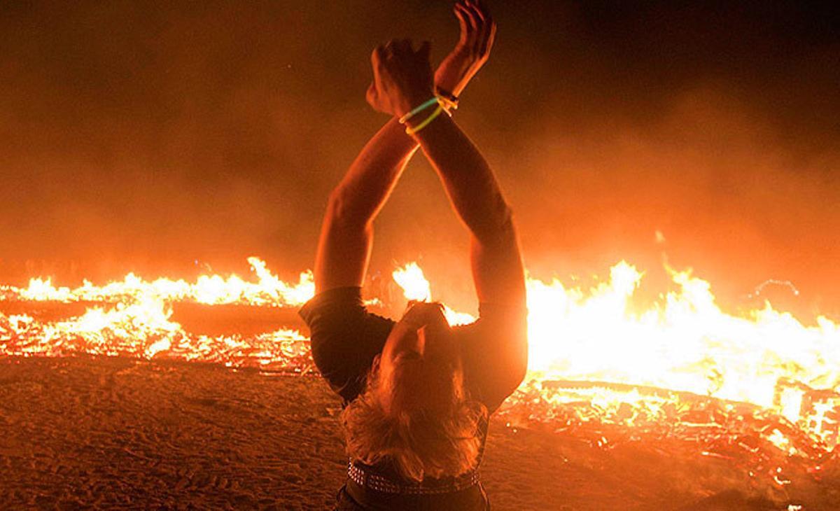 Un home balla al costat del Temple de la Transformació en flames durant el festival d’art i música Burning Man 2011, celebrat al desert de Nevada.