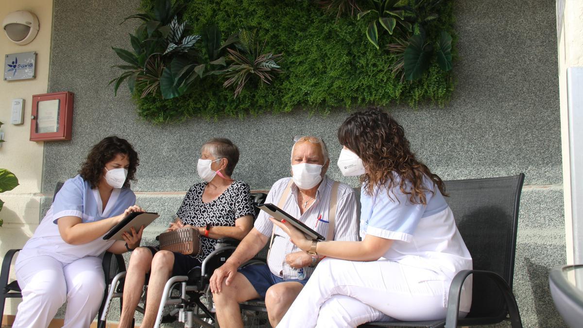 Dos trabajadoras de Savia Picassent junto a residentes del centro.