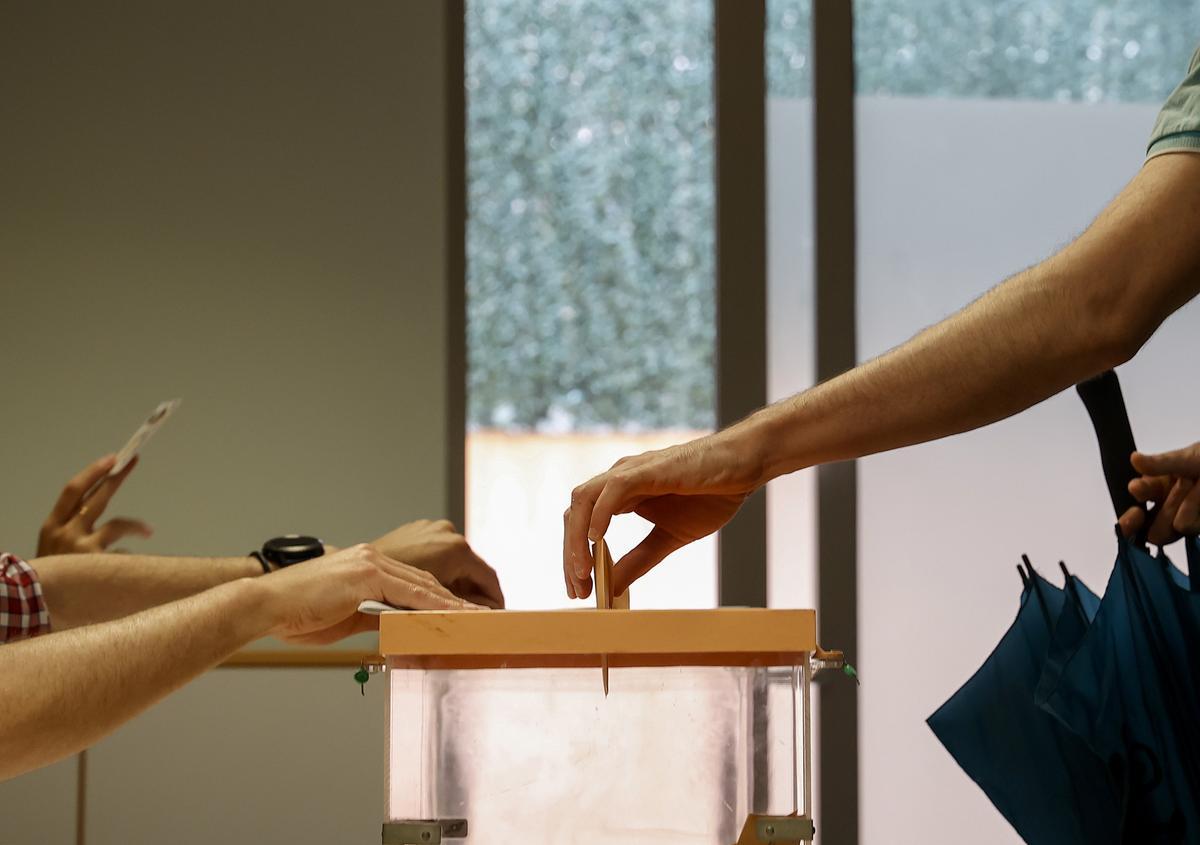 Archivo - Una persona mete su voto en una urna.