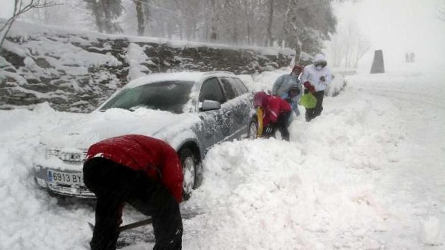 Una familia sacando la nieve para intentar mover su coche en Pedrafita.  // Efe