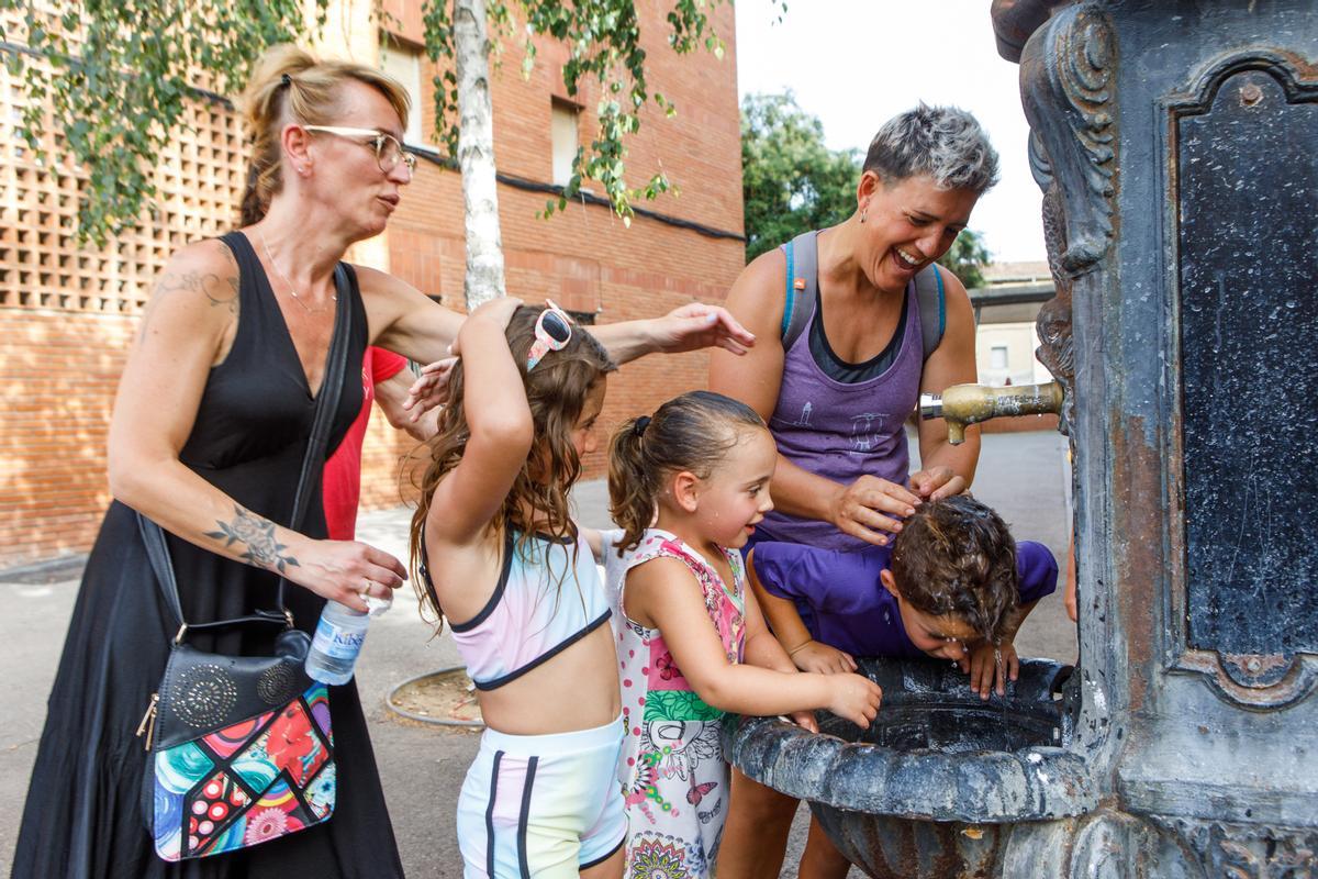 Una madre remoja a su hijo en la fuente en plena ola de calor.