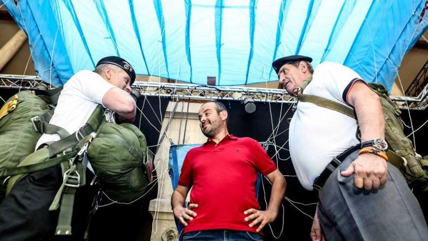 Jorge Fernández Castro -en el centro-, dispuesto a probarse el equipo junto a miembros de Agrupac-Astur, ayer, en el Antiguo Instituto, bajo la tela desplegada de un paracaídas.