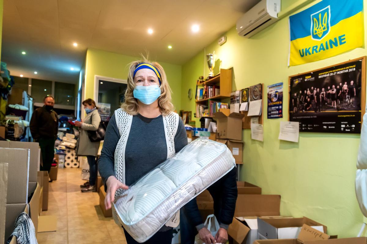 Mariya Layuc, con una cinta con los colores de la bandera de ucrania, clasifica en cajas el material recibido en un centro de recogida de ayuda para Ucrania habilitado en un antiguo locutorio de Guissona.