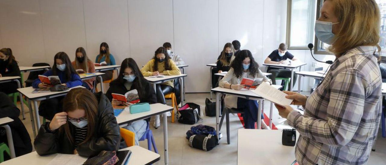 La profesora de Inglés Kathryn Lewis, a la izquierda, durante una clase, y el alumno Diego Baizán, borrando unas fórmulas en una pizarra, ayer, en un  aula de Bachillerato del Corazón de María.