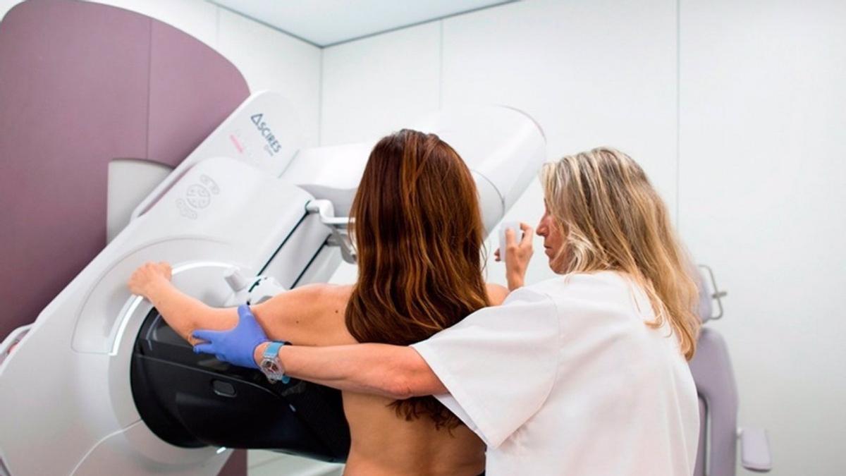Una mujer y una sanitaria durante una mamografía.