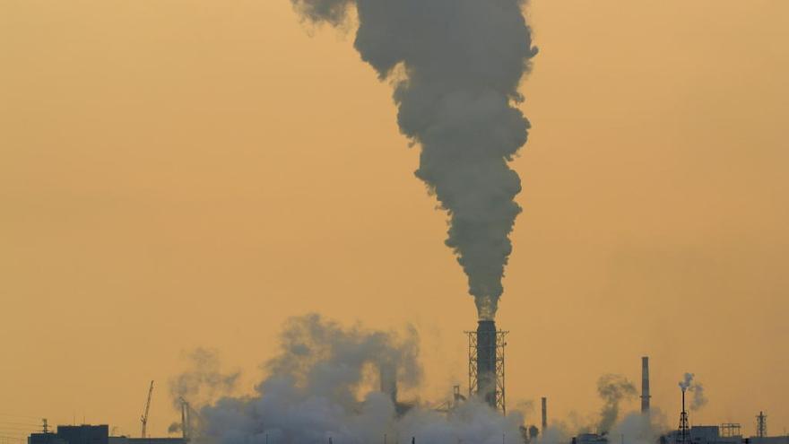 Columna de humo que emana la chimenea de una fábrica en la bahía de Tokio.