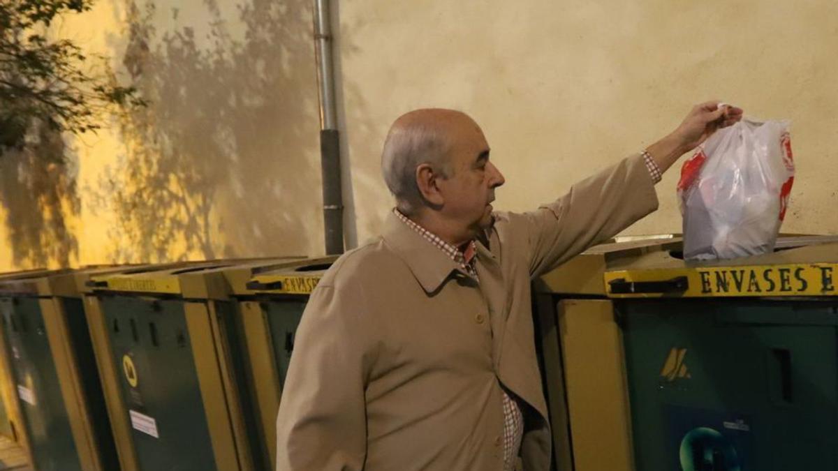 Un hombre deposita una bolsa con residuos en el contenedor de inertes.