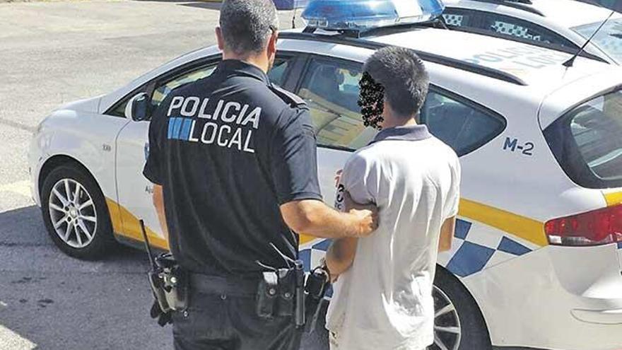 Un policía traslada al comerciante detenido.